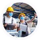 Trabajadores industriales con casco de seguridad revisando documentos en planta de producción