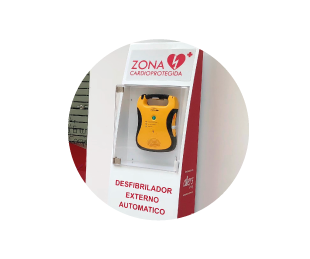 Desfibrilador externo automático instalado en una vitrina marcada como zona cardioprotegida.