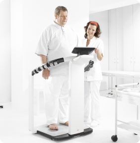 Profesional de la salud utilizando un analizador de composición corporal SECA con un paciente en entorno clínico.